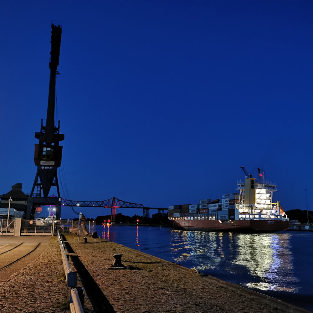 barber using styling spray on young man with black hair, short on sides and long in a quiff on top